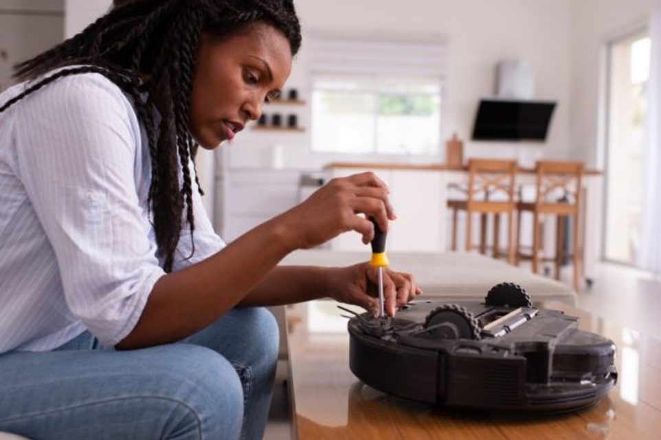Woman fixing a robot vacuum cleaner