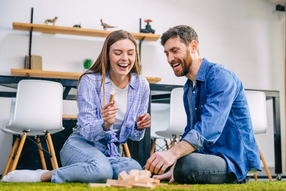 A couple in love sits on the floor, plays a game, builds towers, spends their free time together.